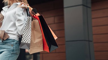 Avrupai bir kadının portresi. Siyah Cuma sezonunun arka planında, alışveriş merkezinin yakınındaki beyaz gömlek kotlarıyla alışveriş yapan kadın.