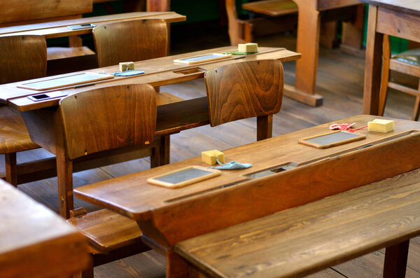 Alte Tische und Stuehle mit Schiefertafeln und Schwamm in einem alten Klassenzimmer