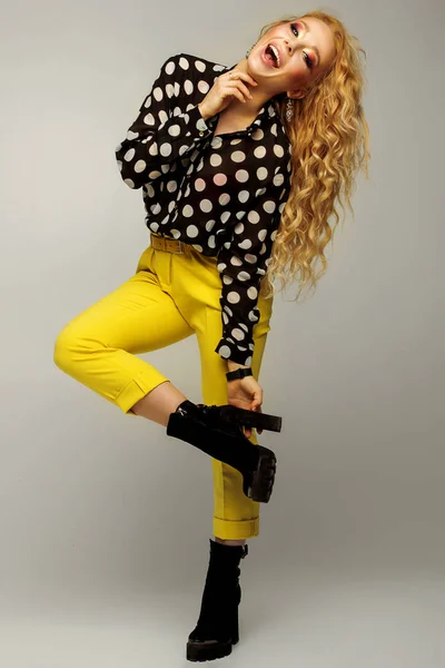 full height. beautiful blonde with a professional make-up in yellow pants and beret, posing on a gray background