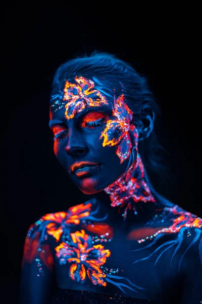 Krásné květiny v UV světle na mladé dívčí tváři a tělo — Stock fotografie