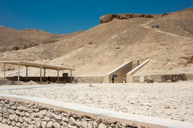 Luxor, Mısır - 27.07.2025. Meşhur Krallar Vadisi 'ndeki antik mezarlardan birinin girişi. Açık mavi gökyüzü ve kayalık manzarası var.