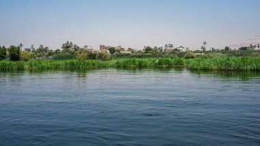 Luxor, Mısır - 27.07.2025. Nil Nehri manzaralı kıyı şeridi boyunca oteller ve binalar ve açık mavi bir gökyüzü.
