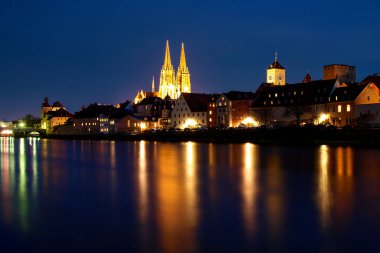 Regensburg, Almanya: Tuna kıyısında günbatımı ışığında tarihi evler, saraylar ve kiliseler.