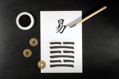 Close up of an I Ching arrangement on slate with the 63th hexagram (After Completition/Chi Chi) written with a chinese ink brush on rice paper. There is also a chinese ink tank.  clipart