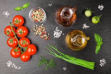 Kaba tuz taneleri, bir yağ ve sirke sürahisi, renkli biber, dereotu, soğan ve fesleğenli bir dal domates..
