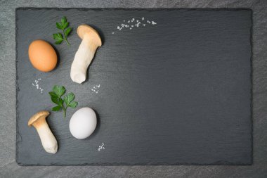 İki Kral İstiridye Mantarı ve bir beyaz ve bir kahverengi yumurta. Tuz taneleri ve maydanoz yapraklarıyla. Telif aletiyle. Düz yatıyordu..