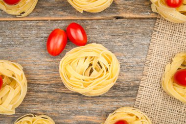 Yumurta şekilli mini roma domatesli tagliatelle eriştesi yuvasıyla ahşap bir çuval bezi üzerinde kapatıyoruz.