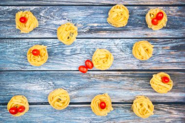 Yumurta şeklinde mini roma domatesli tagliatelle erişteleri yıpranmış mavimsi bir masada..