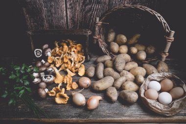Tahta bir masada patates, mantar, yumurta, maydanoz, soğan ve soğan.