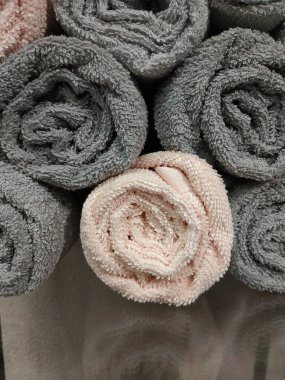 Askıda gri ve pembe renkli temiz havlular var.