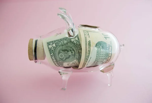 transparent money box with money on pink background