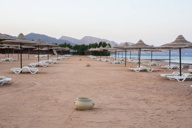 Mısır tatil beldesinde beyaz şezlonglar, kil kutular ve saman şemsiyeler