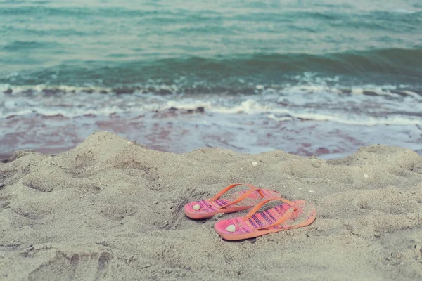 海と波の景色とシェルとビーチの砂で失われた 左ピンクとオレンジの女性のフリップフロップ 泳ぎに行く 幸せな休暇 柔らかい色 — ストック写真