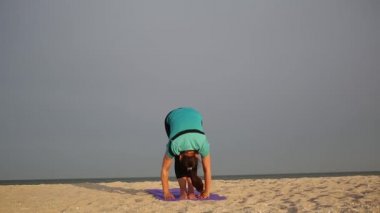 Kadın yoga egzersizi yapıyor. Sabah ibadeti, güneş tarikatı aktif tatil, kumlu sahilde egzersiz ve sıcak ışık altında spor minderi.  