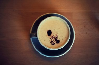 En iyi çay tabağı manzarası ve sütlü kahve köpüğü ve tarçınlı çikolata damlası ahşap masa arkasında latte sanatı.