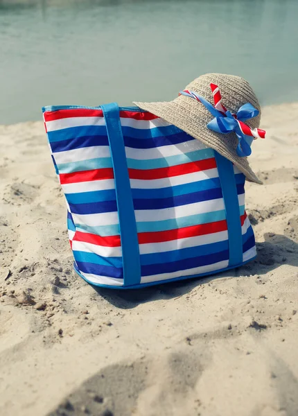 リボン ビーチファッション 休暇のコンセプト 砂と海の背景とストライプのキャンバスバッグとわら帽子で女の子のアクセサリーを閉じます — ストック写真