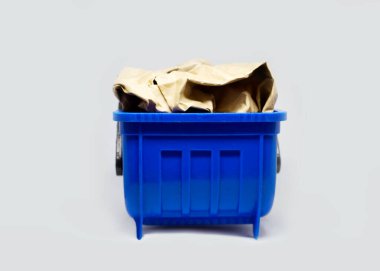 Mavi plastik oyuncak çöp kutusu kağıt karton çöplerle dolu teneke kutu izole arka plan, çöp geri dönüşüm ekolojik konsept