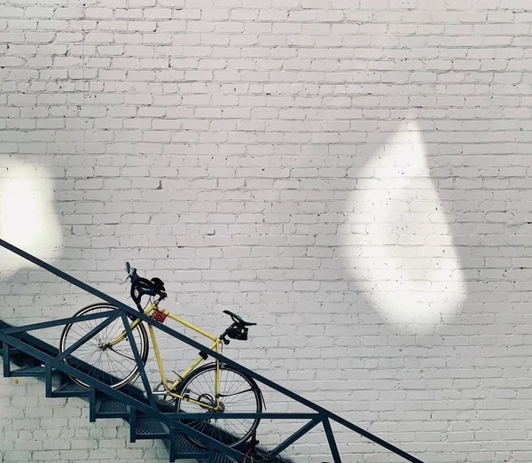 Bicicleta Unisex Amarela Nas Escadas Fundo Branco Parede Dos Tijolos — Fotografia de Stock