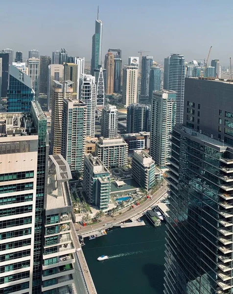 Dubai, BAE - 08.04.2020: Dubai Marina 'daki gökdelenler arasında yelken açan beyaz tekne, modern şehir manzarası