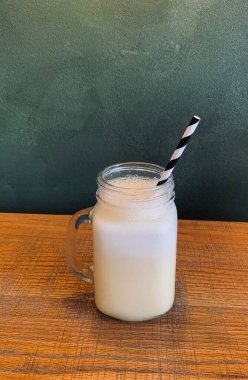 Hindistancevizi, ananas, ahşap masada yeşil beton arka planda kağıt kamış ile pina colada beyaz içecek 