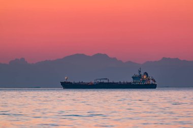 Dağlar n arka plan ile akşam denizde yüzen kargo gemisi