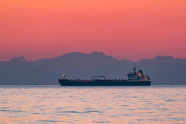 Dağlar n arka plan ile akşam denizde yüzen kargo gemisi