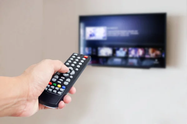 hand hold remote control with TV on wall