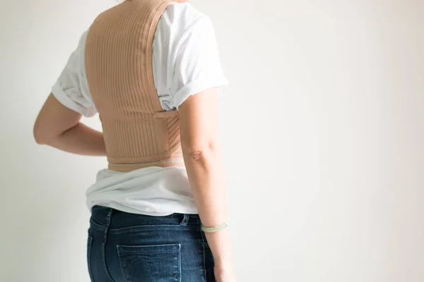 A woman wearing back support corsets for protect her back and reduce back pain.