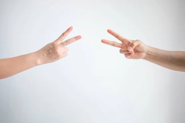 Two person playing rock paper scissors with both posturing scissors symbol on white background.