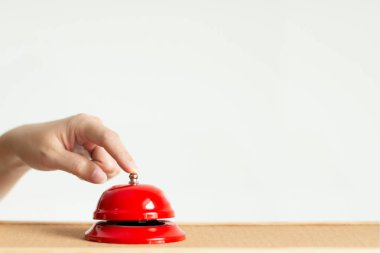 Ahşap masa üzerinde kırmızı vintage tarzı handbell çan düğmesine basarak işaret parmağı yakın çekim.