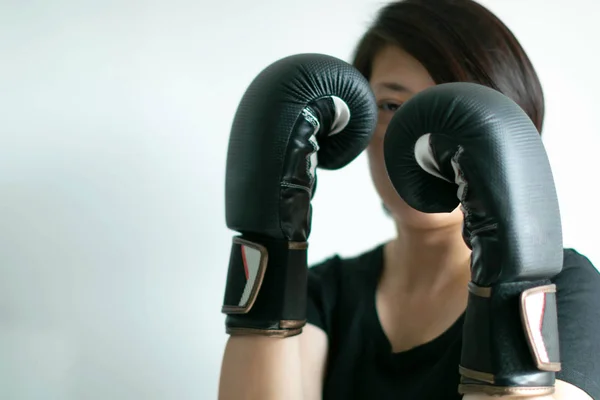 Una mujer en guantes de boxeo posando guardia de boxeo y mantener un ojo en la captura del objetivo . —  Fotos de Stock