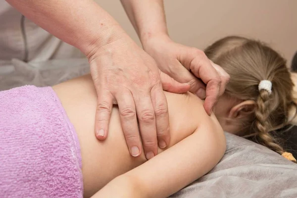 The masseur gives the child a back massage — Stock Photo, Image