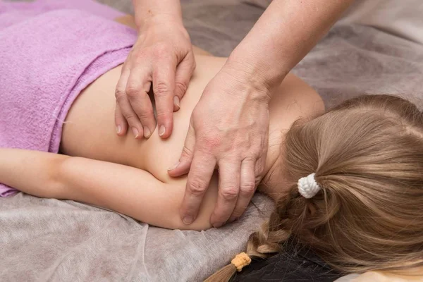 masör çocuk bir sırt masajı verir.