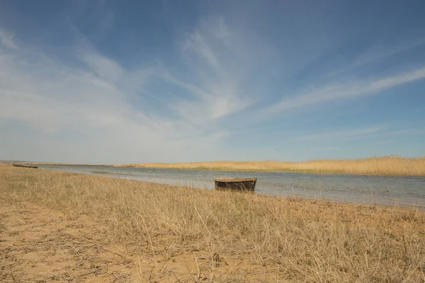 El barco en el agua. Botes de remos en las cañas. Barco de madera en el lago en un día de verano. Mar de Aral, Kazajstán — Foto de Stock