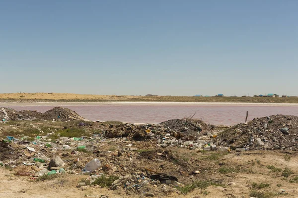 Illegal garbage dump near the water technical lake with pink water