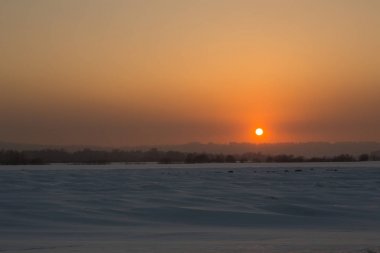 Karla kaplı bir alanda kışın parlak gün batımı