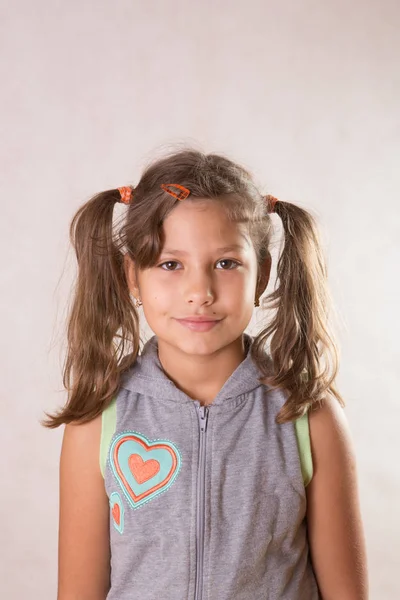 Carino bambina sorridente guardando con due trecce sciatte — Foto Stock