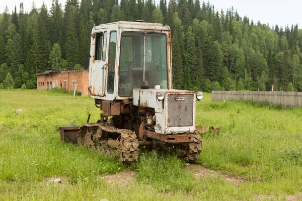 Trator velho em um campo na aldeia no verão — Fotografia de Stock