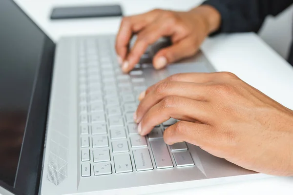 hands of a black african woman typing on the keyboard of a modern laptop