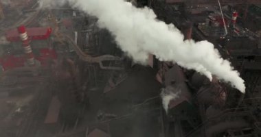 Hava kirliliği. Bitkinin bacalarından duman bulutları geliyor. İnsansız hava aracı çelik fabrikasının bacalarının üzerinde uçuyor..