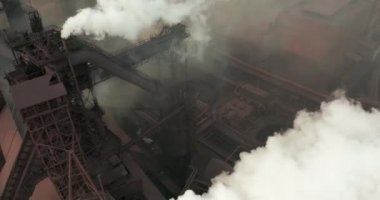 Hava kirliliği. Bitkinin bacalarından duman bulutları geliyor. İnsansız hava aracı çelik fabrikasının bacalarının üzerinde uçuyor.