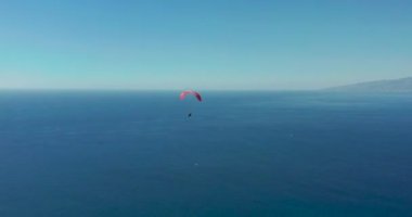Açık mavi gökyüzüne karşı uçan olağanüstü paraglider.