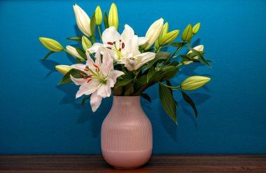 Mavi bir duvarın önünde bir buket zambak