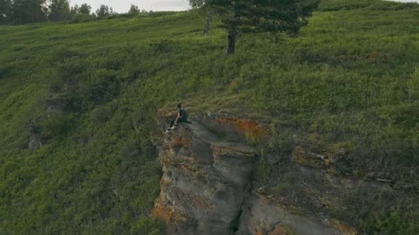一个女孩坐在西伯利亚针叶林中一座山上的岩石上 — 图库视频影像