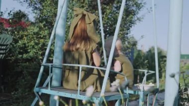 İki çocuk sallanıyor salıncakta