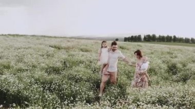 İki çocuklu genç bir aile papatya tarlasında yürüyor.