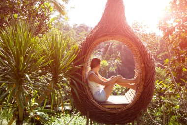 Kot şortlu güzel bir kadın ormanın arka planında oturuyor.