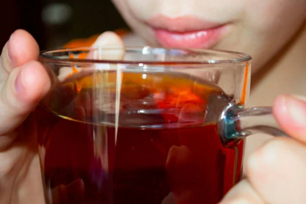  Şeffaf büyük bir bardaktan siyah çay içen bir kızın fotoğrafı. Kapat.