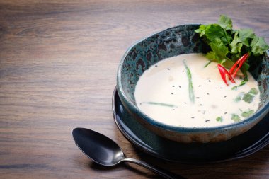 Tom Kha çorba kasesi ahşap masa arkasında. Geleneksel Tayland baharatlı Hindistan cevizi sütü çorbası. Tom Kha Gai. Restoran menüsü. Kapat, boşluğu kopyala