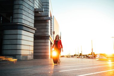 Havaalanında bir bavul çekerek iyi giyimli iş kadını tam uzunlukta portresi.